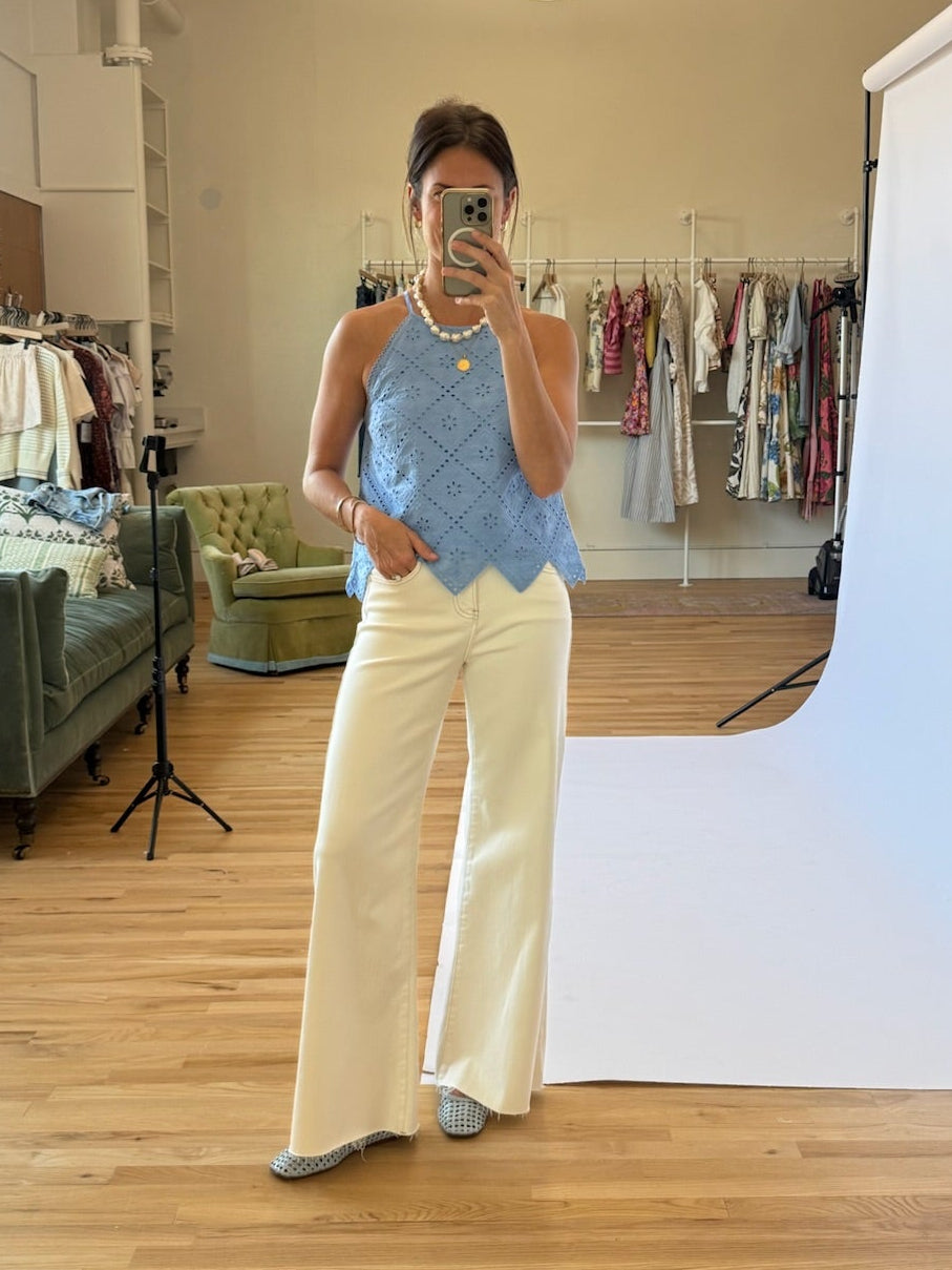 Person taking a mirror selfie in a room with a white backdrop and clothing rack.